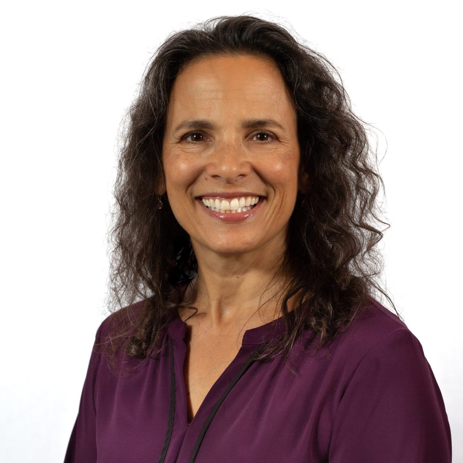 SKravits-headshot-for-ACTP-2025-scaled-e1740514359912-1536x1536 A woman in purple shirt smiling for the camera.