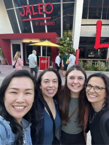 Four women are taking a selfie in front of a restaurant.
