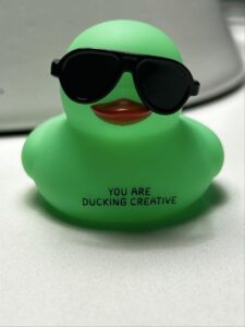 A green rubber duck with sunglasses on it.
