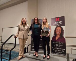 Three women standing in front of a sign.