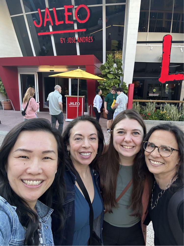 Four women are taking a selfie in front of a restaurant.