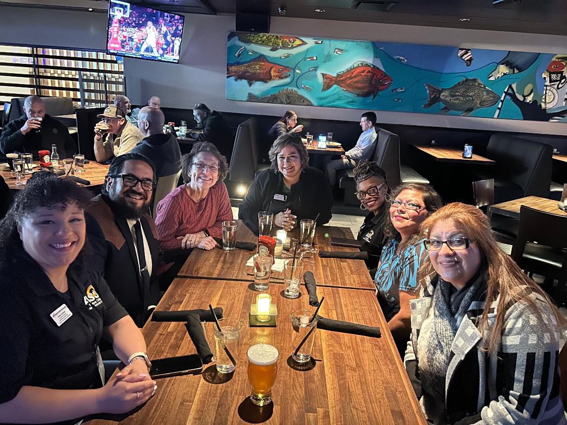 Group of people smiling at restaurant table.