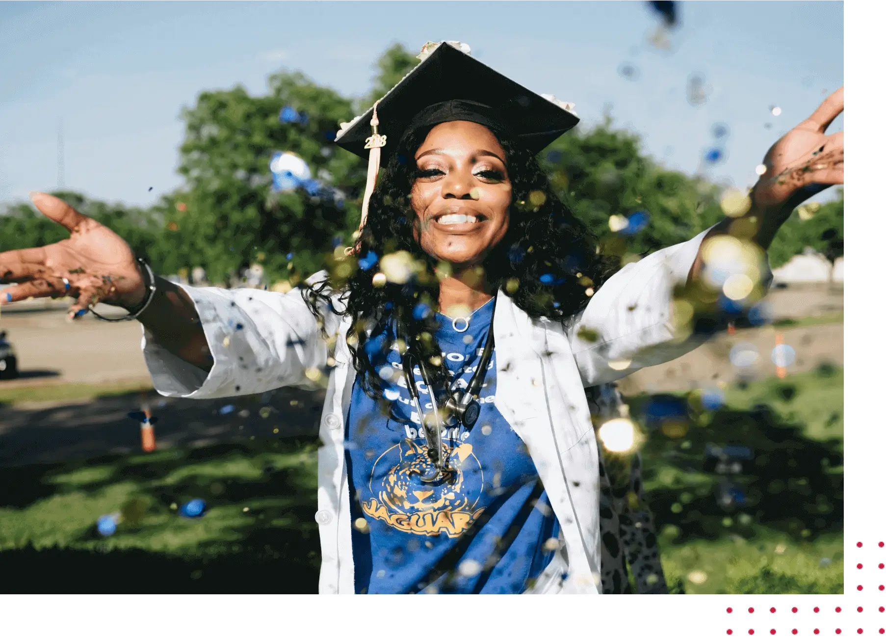 A woman in graduation cap and gown throwing confetti.