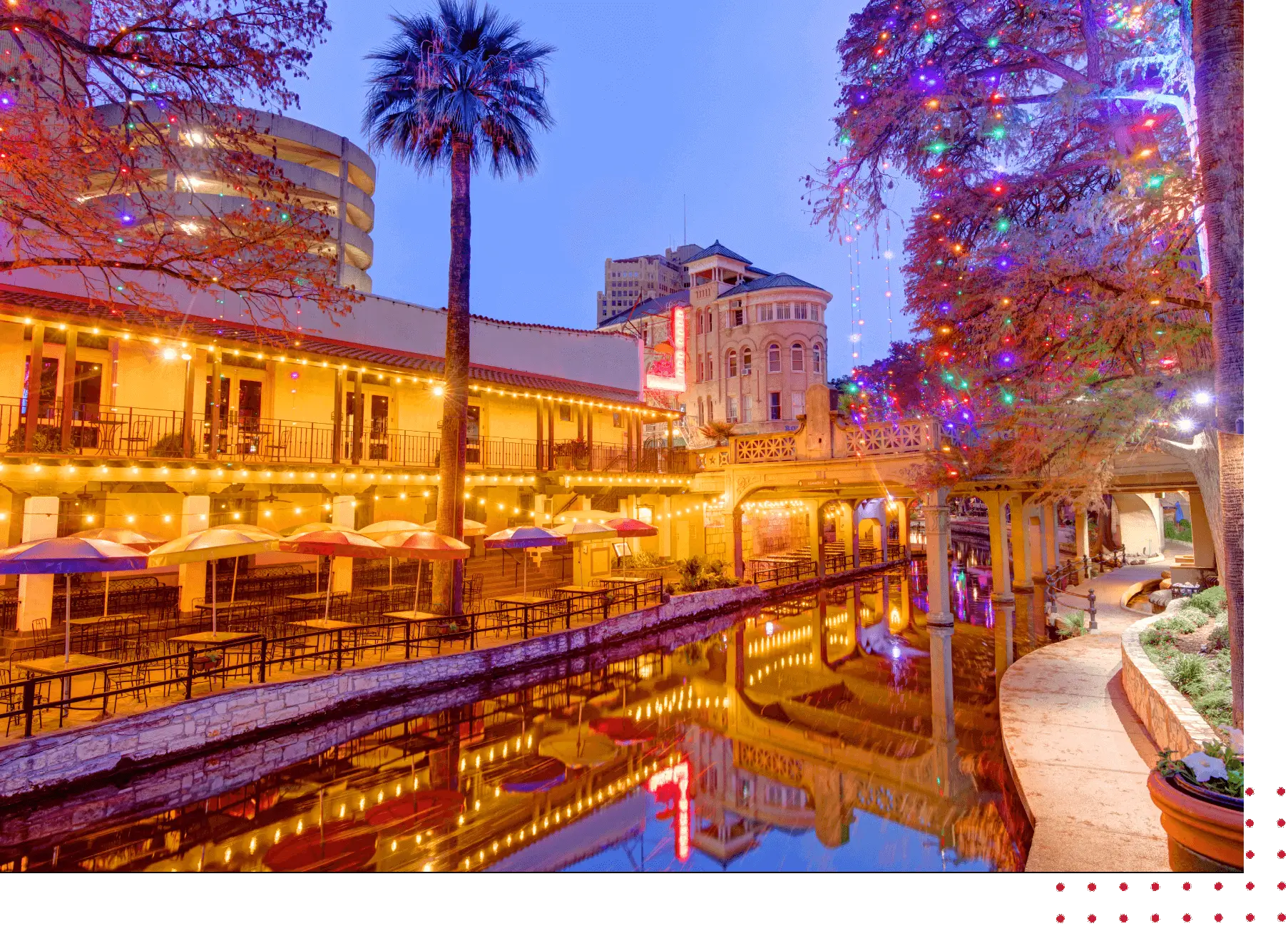 Colorful lights reflecting on a riverside walkway.